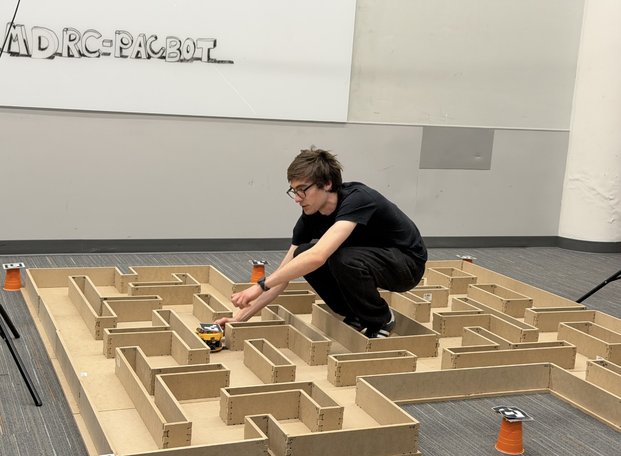 PacBot team member testing the robot in a wooden maze